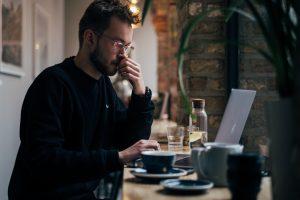 Emprendedor con gafas evalúa si constituir autónomo o sociedad limitada con ayuda de MiempresaYA desde un café