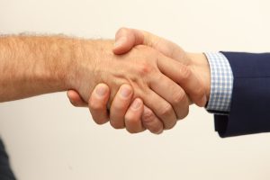 Dos socios sellando un acuerdo de mano al crear su empresa en Madrid con ayuda de MiempresaYA