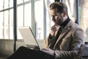 Empresario pensativo con laptop valorando iniciar un concurso de acreedores voluntario, asesorado por MiempresaYA